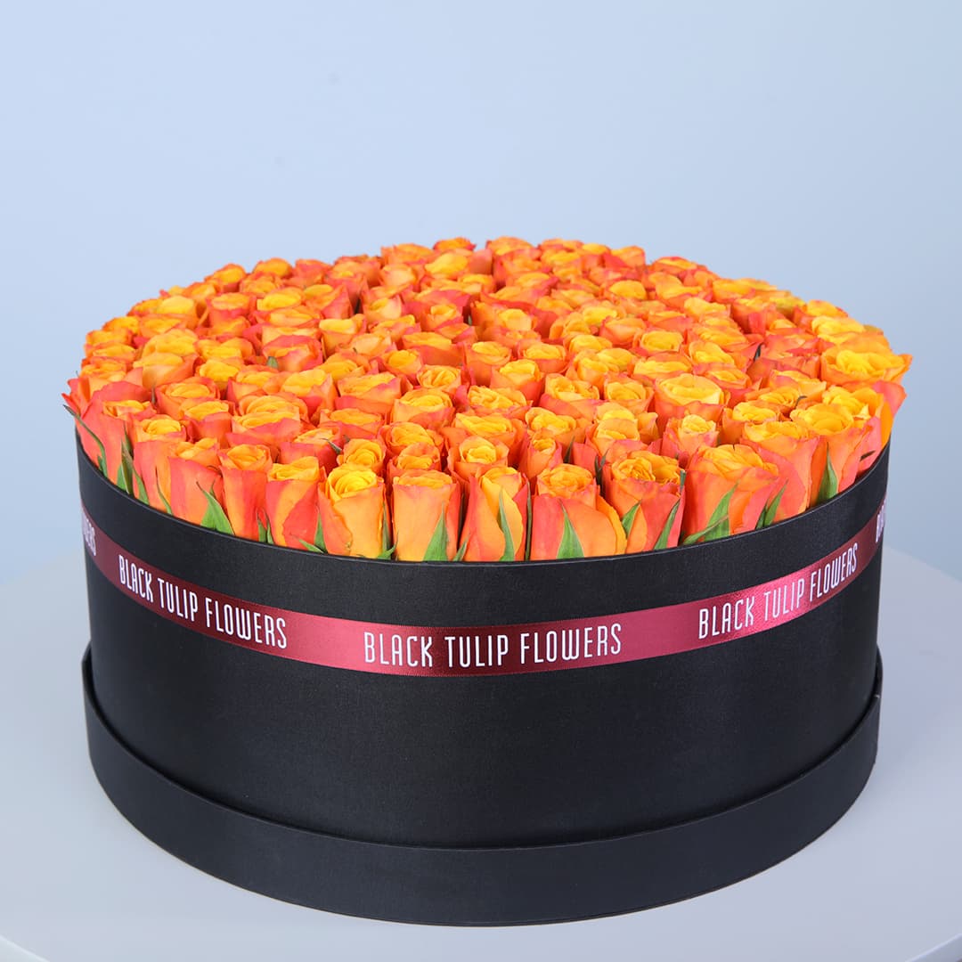 120 orange roses in a black hat box with Pink ribbon