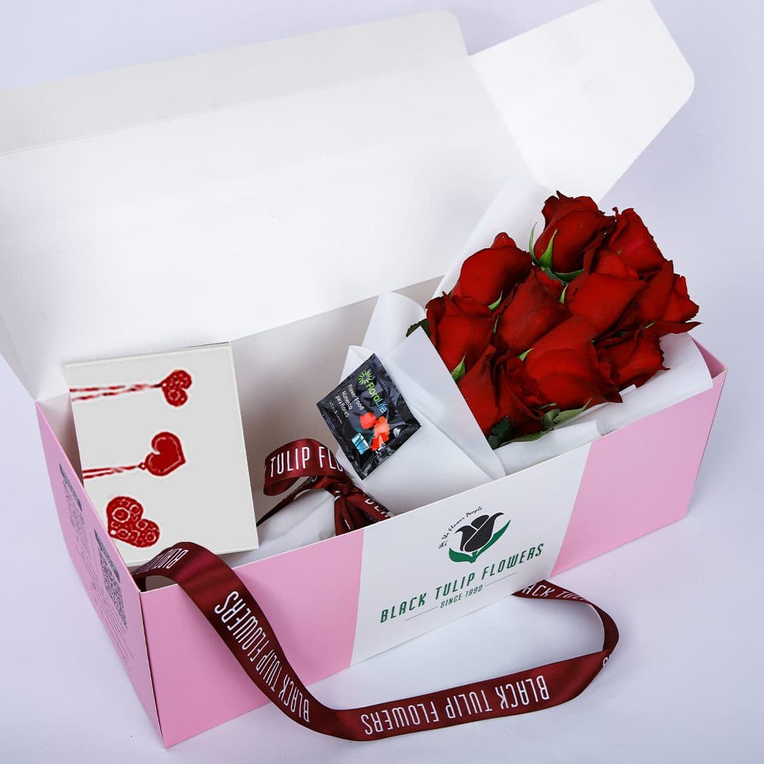 10 stunning red roses wrapped in white and tied with a maroon ribbon, beautifully presented in a pink box with a greeting card.