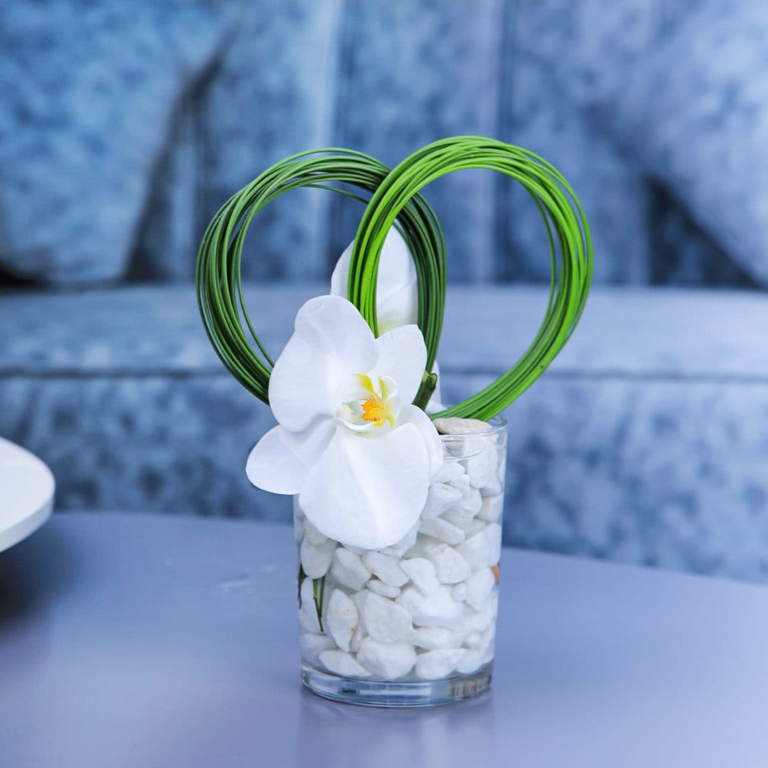 Centerpiece made with of Phalaenopsis White flower with white pebbles and green leaves