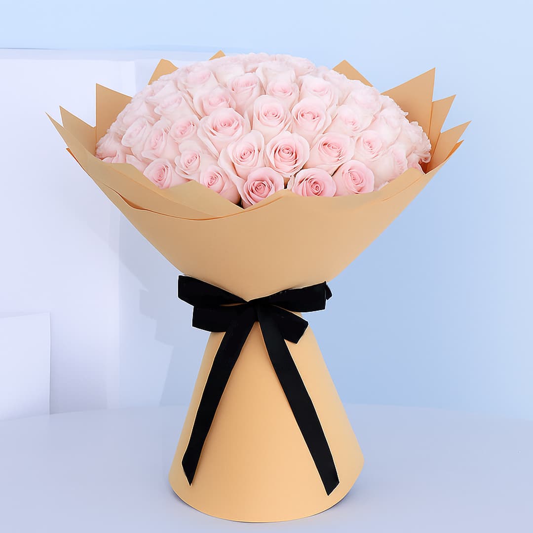 Bouquet of light pink roses wrapped in brown paper with a black ribbon.