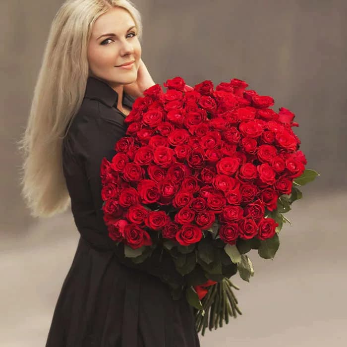 Bunch of 100 red roses elegantly tied with red ribbon.