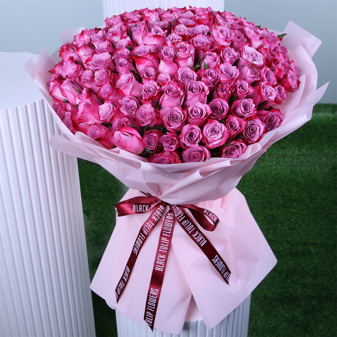 A luxurious Women's Day bouquet featuring soft pink roses, wrapped in blush pink paper and finished with a chic maroon ribbon.