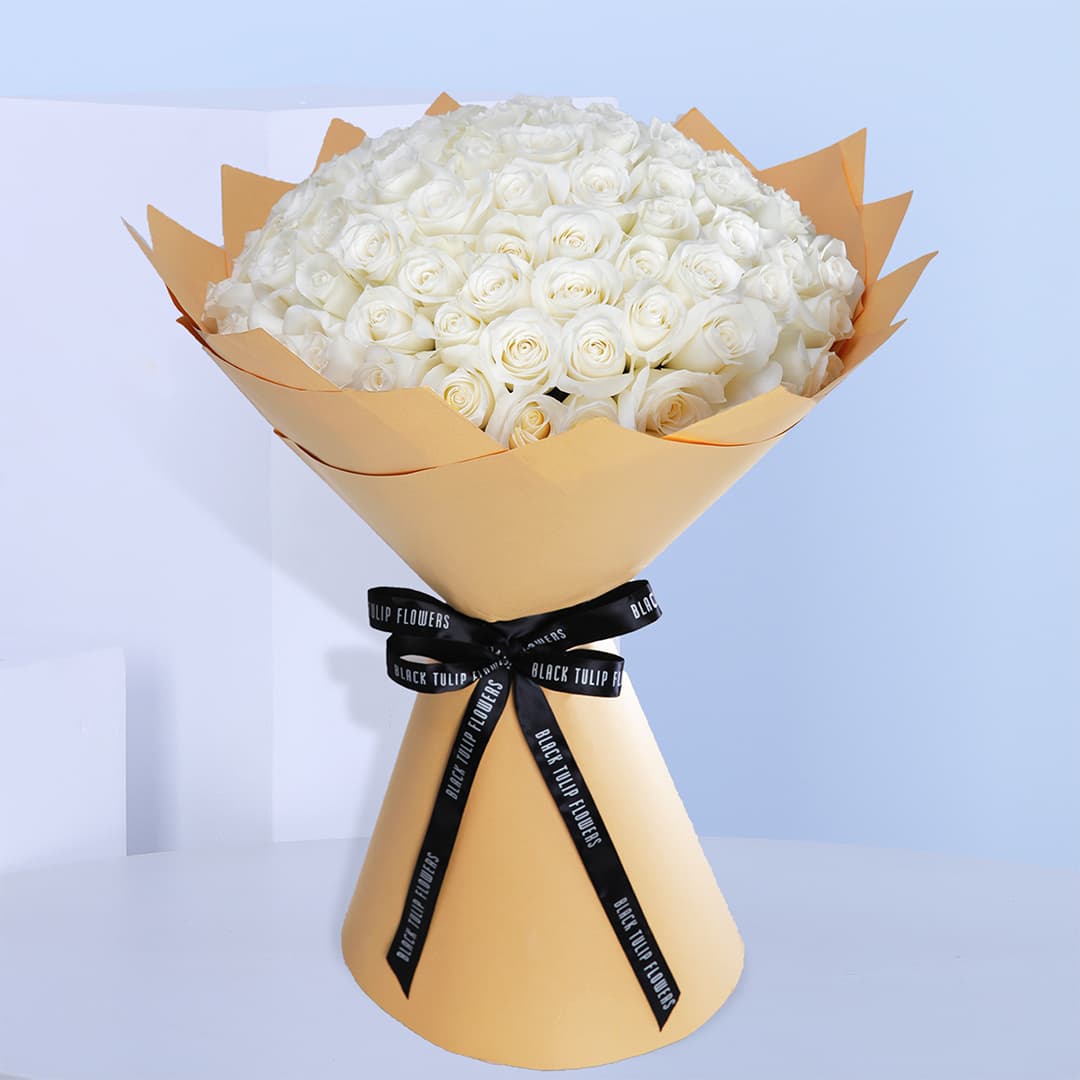 White rose bouquet in a brown wrap tied with black ribbon.