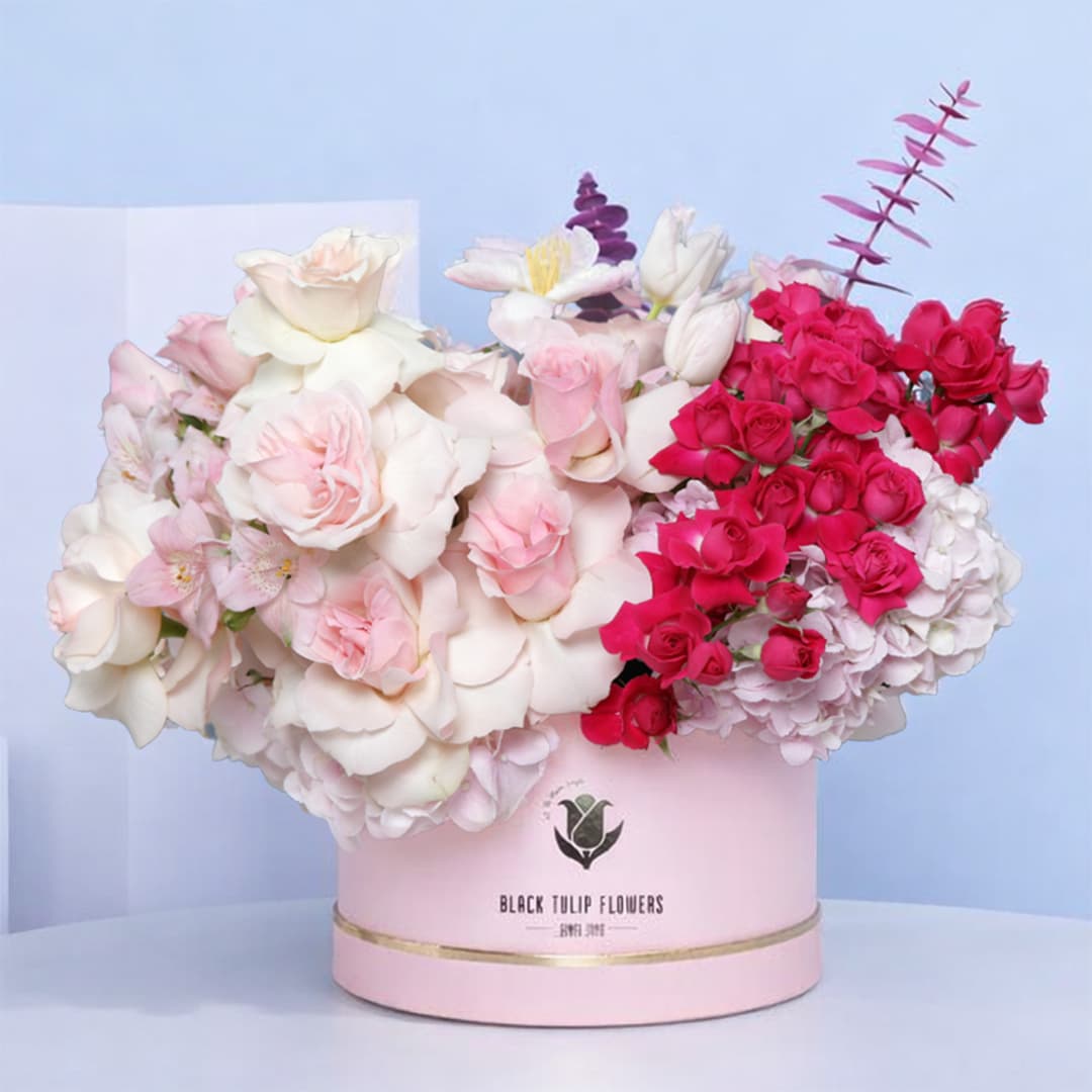 A beautiful "Pink Box" filled with light pink roses, dark pink spray roses, pink tulips, pink hydrangeas, and eucalyptus.
