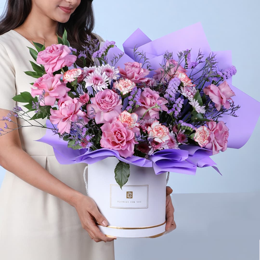 Colorful bouquet of purple roses paired with double color carnations, chrysanthemum lollipops, and soft purple filler flowers for a textured floral display.