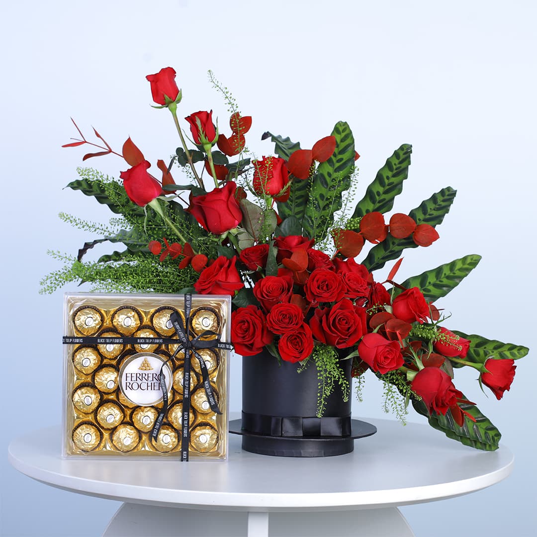 25 red roses, vibrant eucalyptus, lush greens, in a black hat box with Ferrero Rocher chocolates.