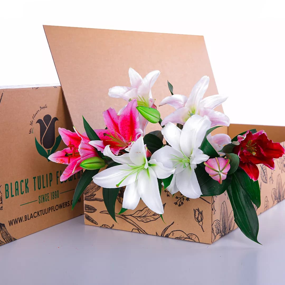 A Mixed bouquet of pink and white lilies, arranged in a cardboard box.
