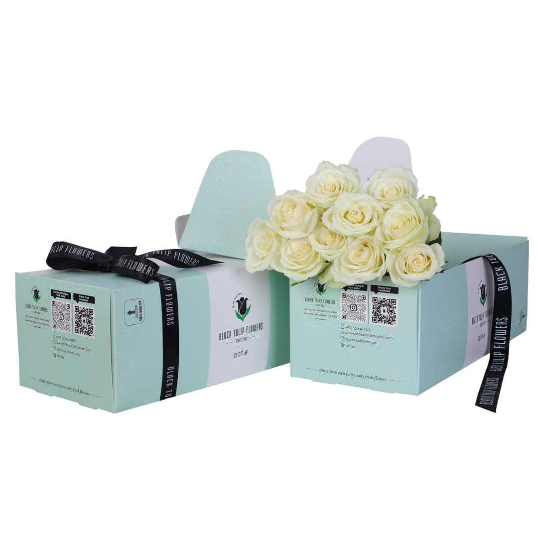 White rose bunch on a green box with flower food and tied with black ribbon.