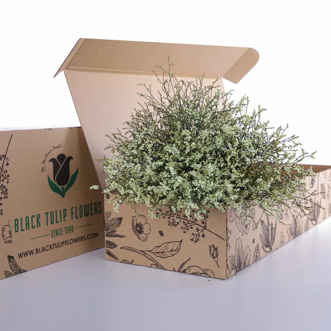 A cardboard box filled with vibrant yellow Limonium flowers, showcasing their delicate beauty and fresh appearance.