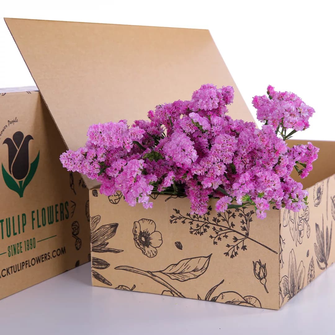 A bunch of pink Statice flowers arranged in a cardboard box, emphasizing their beauty and freshness.