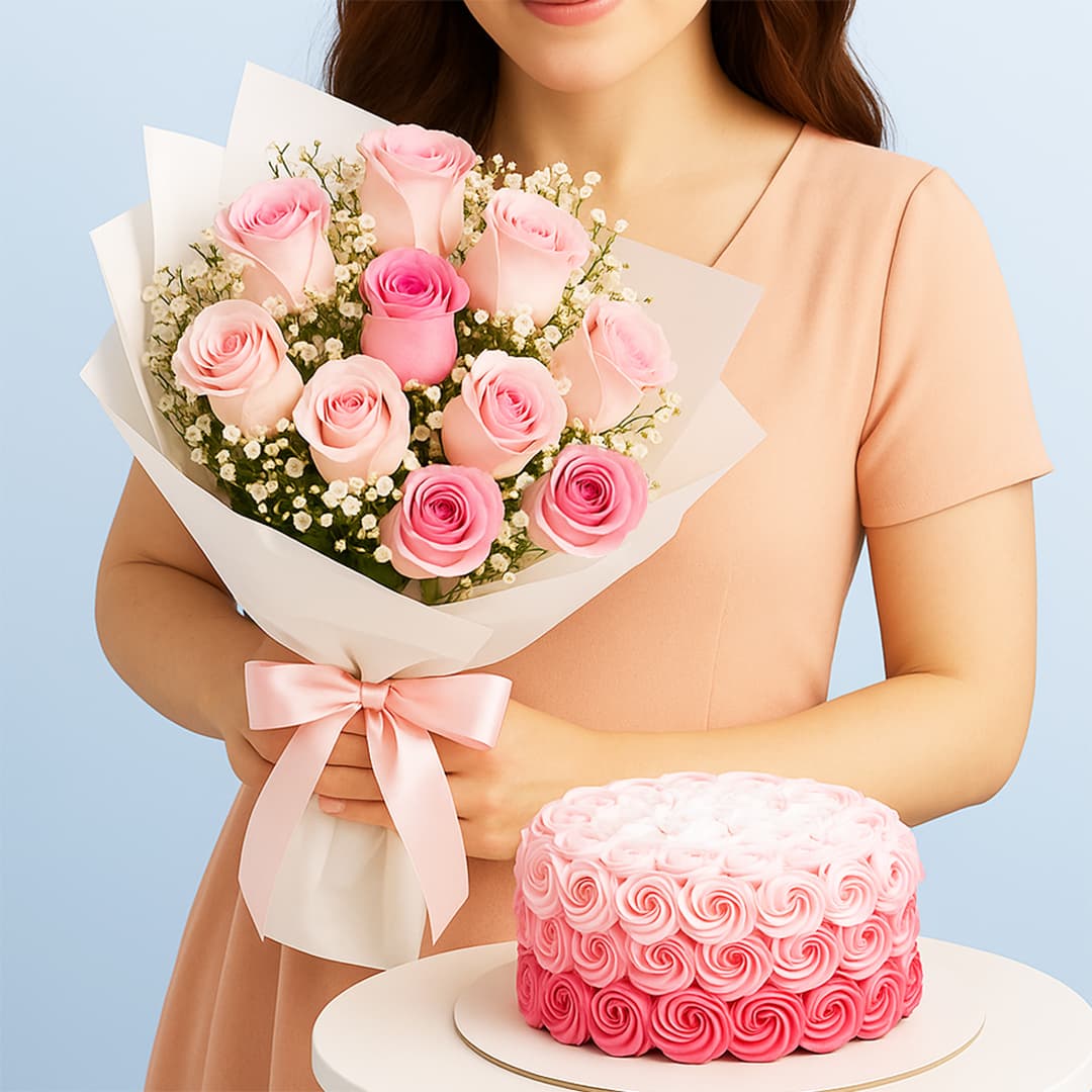 A woman holding a bouquet of light and dark pink roses with baby's breath wrapped in white paper with a pink ribbon and a round cake decorated with pink ombre rosettes.