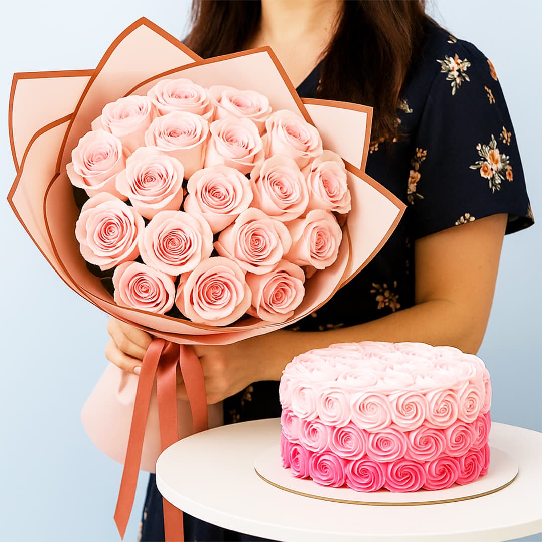 A woman holds a large bouquet of light pink roses wrapped in pink and brown with round ombre cake with pink rosettes.