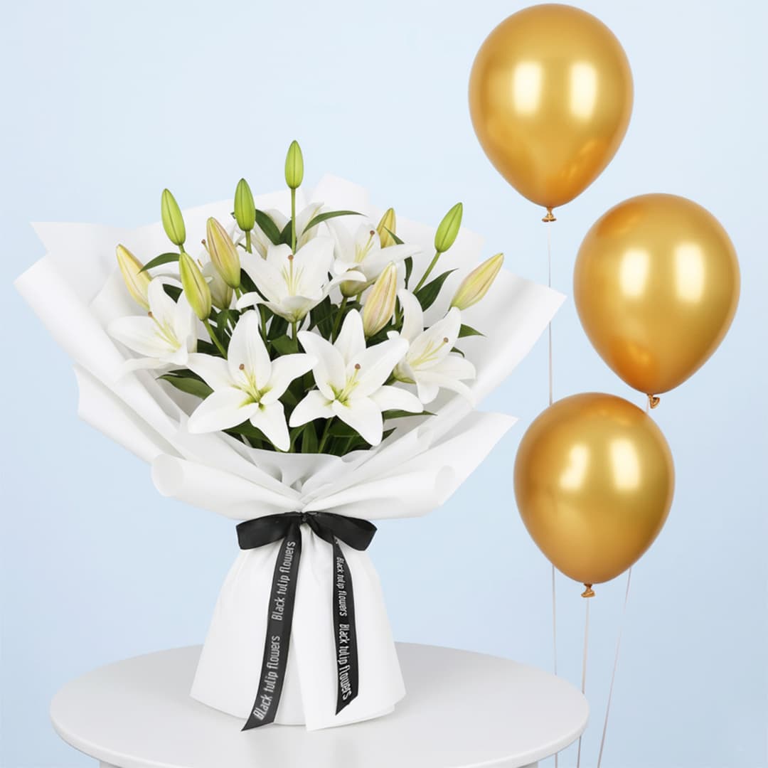 A combo featuring a vibrant white lily bouquet with blooming lilies and green buds, wrapped in white and with a black ribbon and three shiny gold balloons.