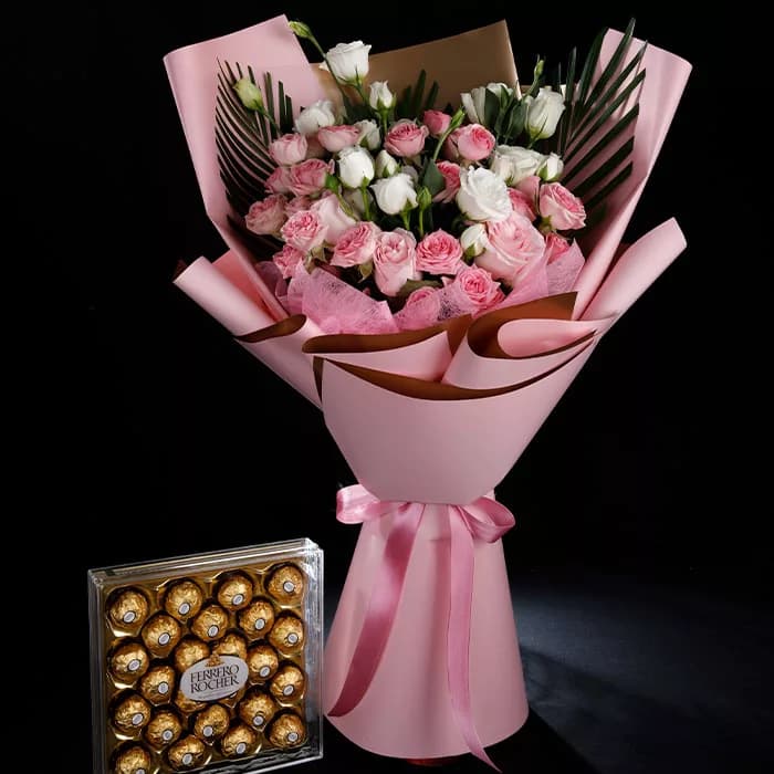 Pink and white spray roses with lush greenery in a pink wrap tied with pink ribbon paired with 24 Ferrero Rocher chocolates.