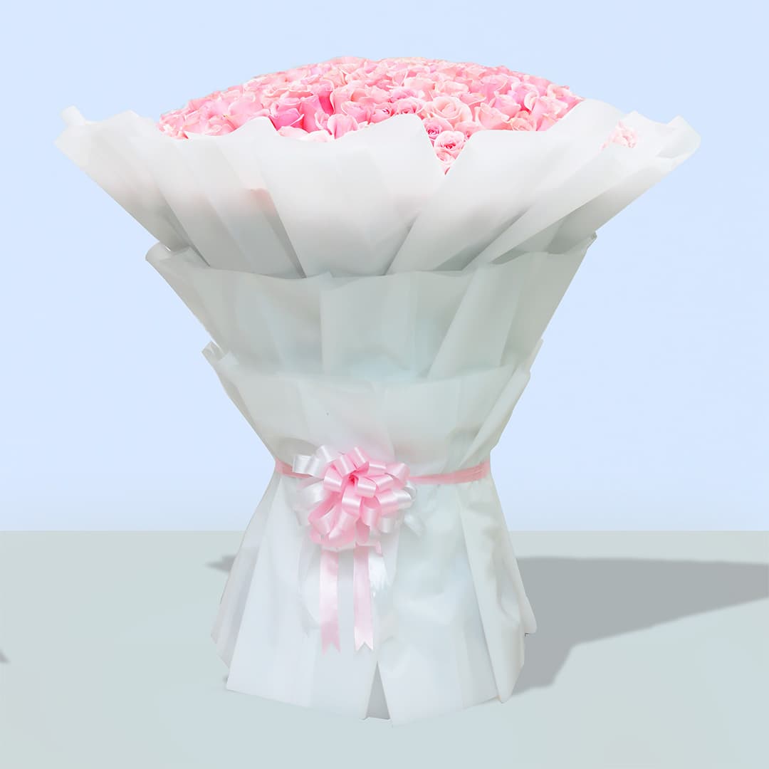 A large bouquet of 100 pink roses, wrapped in white paper with a pink ribbon, standing on a wheeled stand.