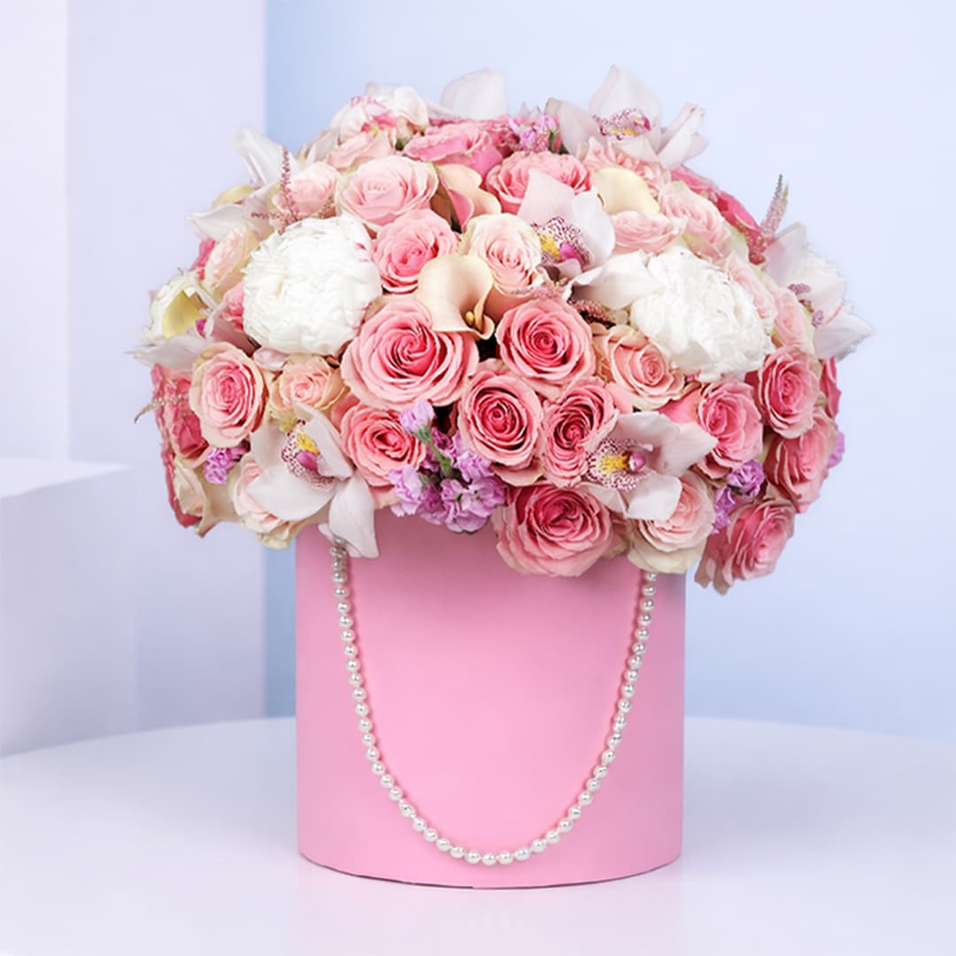 Luxurious pink rose and orchid arrangement in a pearl-adorned round pink box.
