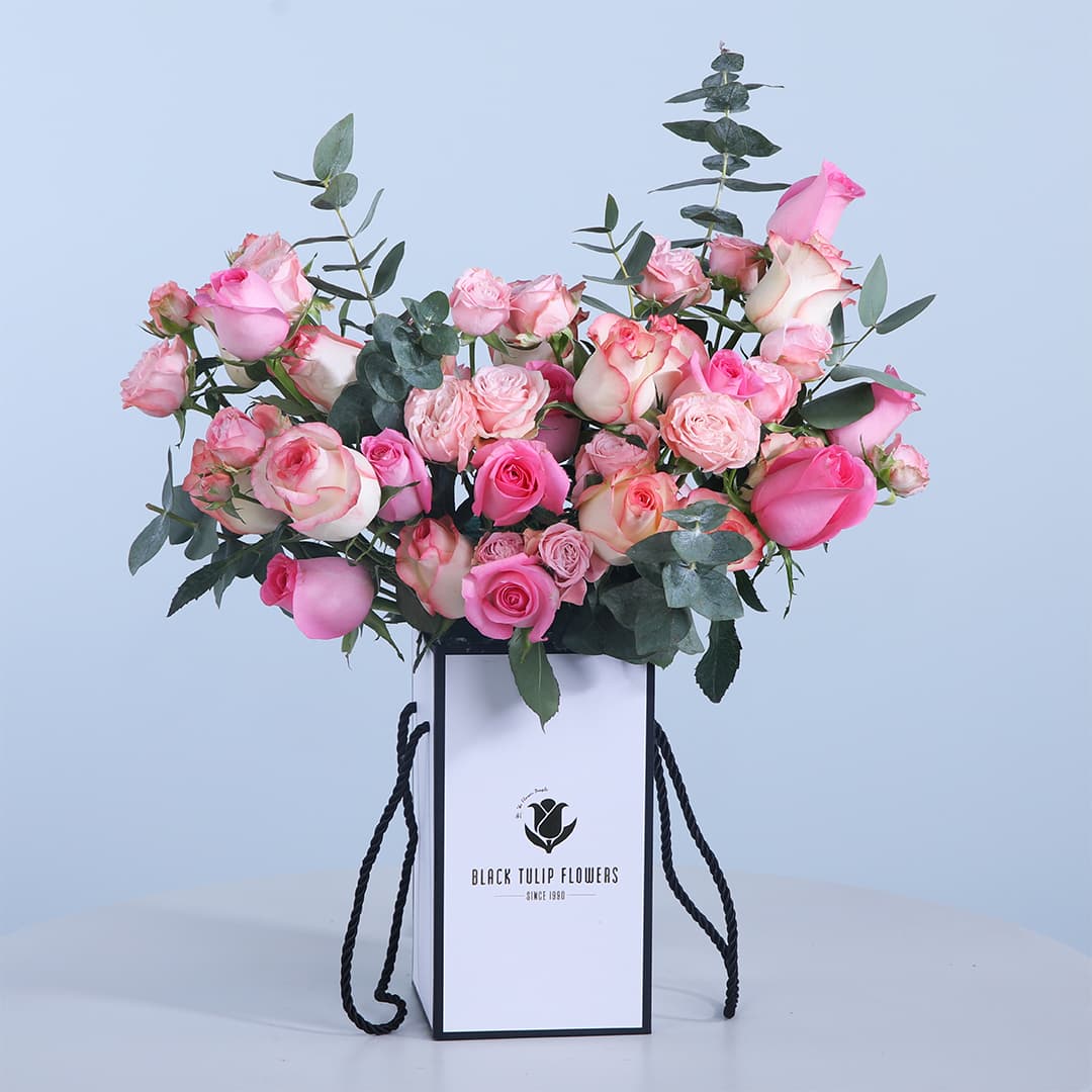 Box of pink roses, Jumelia roses, baby roses, and fresh leaves.