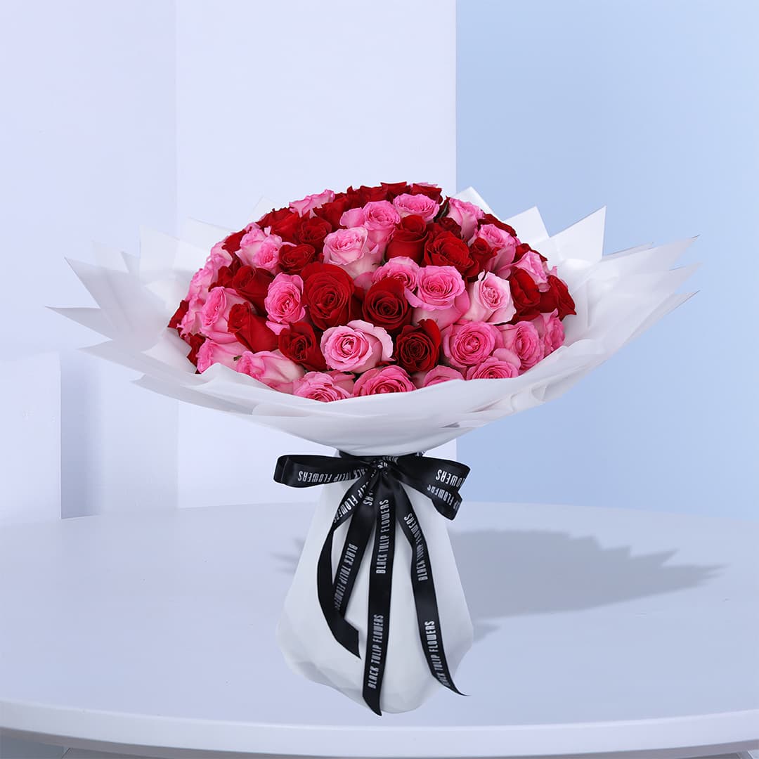 Elegant mix of red and pink roses, wrapped in white and tied with a black ribbon.