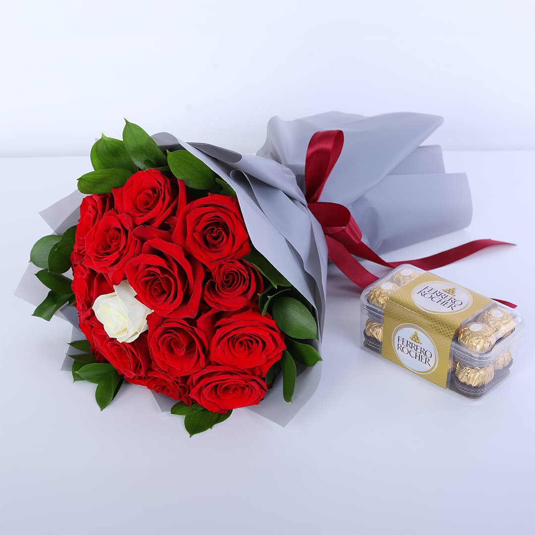 Bouquet of 14 red roses, 1 white rose, ruscus leaves and Ferrero Rocher chocolates in a grey wrap with a red ribbon.