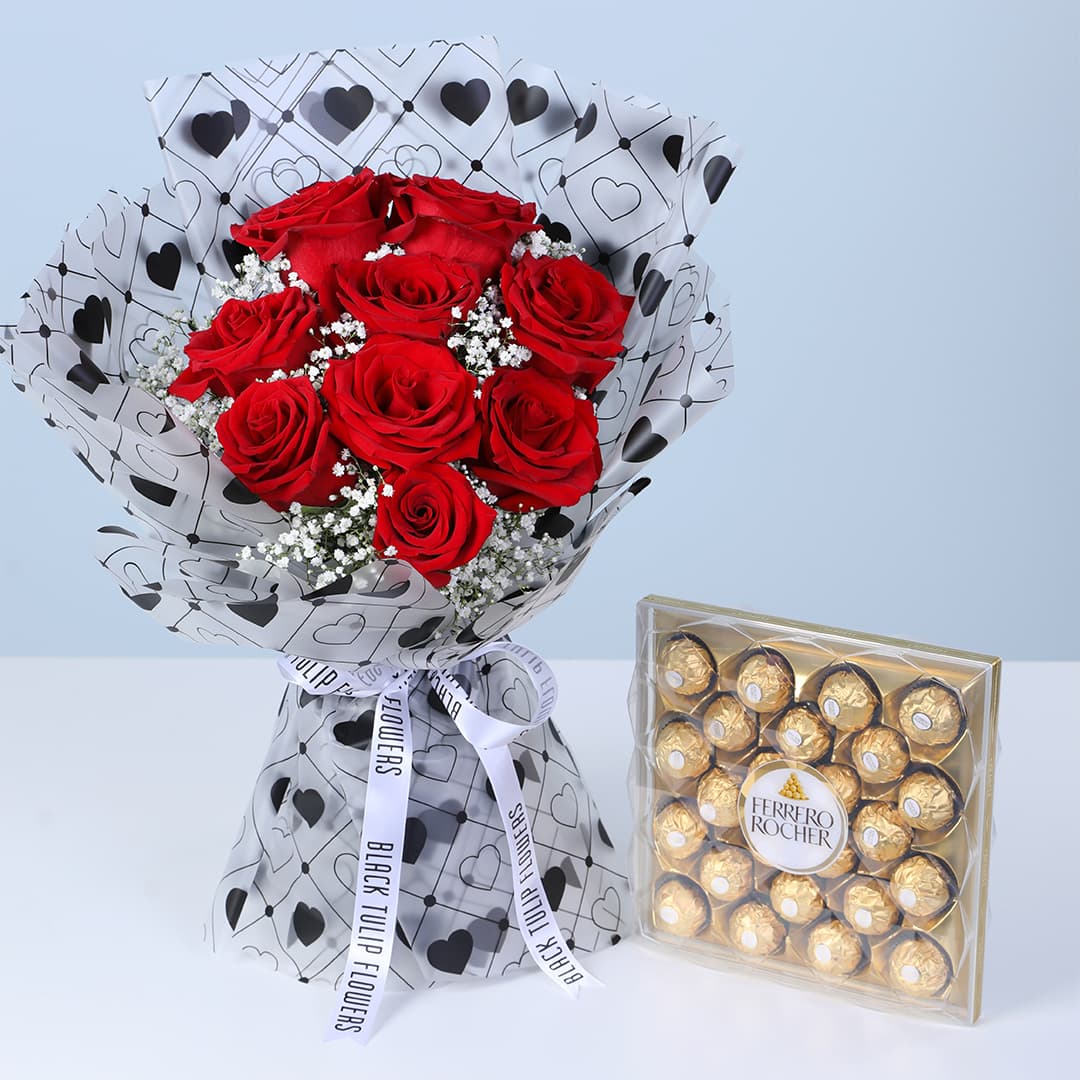 Red roses and baby’s breath bouquet in a heart-patterned white wrap, with a premium Ferrero chocolate box for Valentine’s Day.
